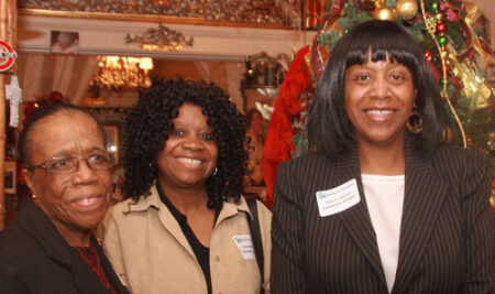 Three African American woman in front of a Christmas tree.