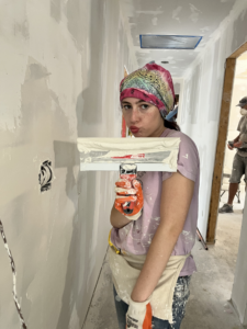 Young girl smiling into the camera while holding a drill.