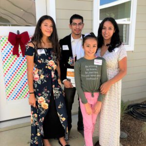 Hispanic family standing in front of new home.
