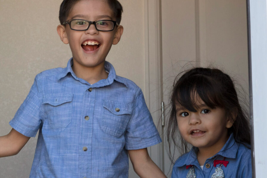 a smiling little boy and girl both wearing blue shirts