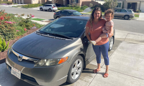 Mom hold her little daughter smiling in front of Honda Civic.