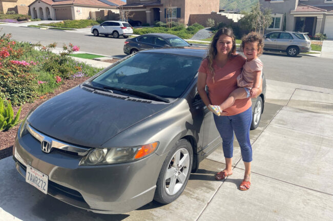 Mom hold her little daughter smiling in front of Honda Civic.