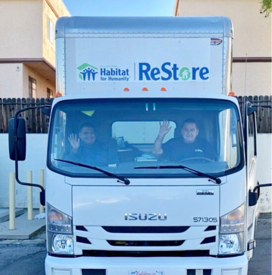 Two men waving in the San Gabriel Valley Restore truck.
