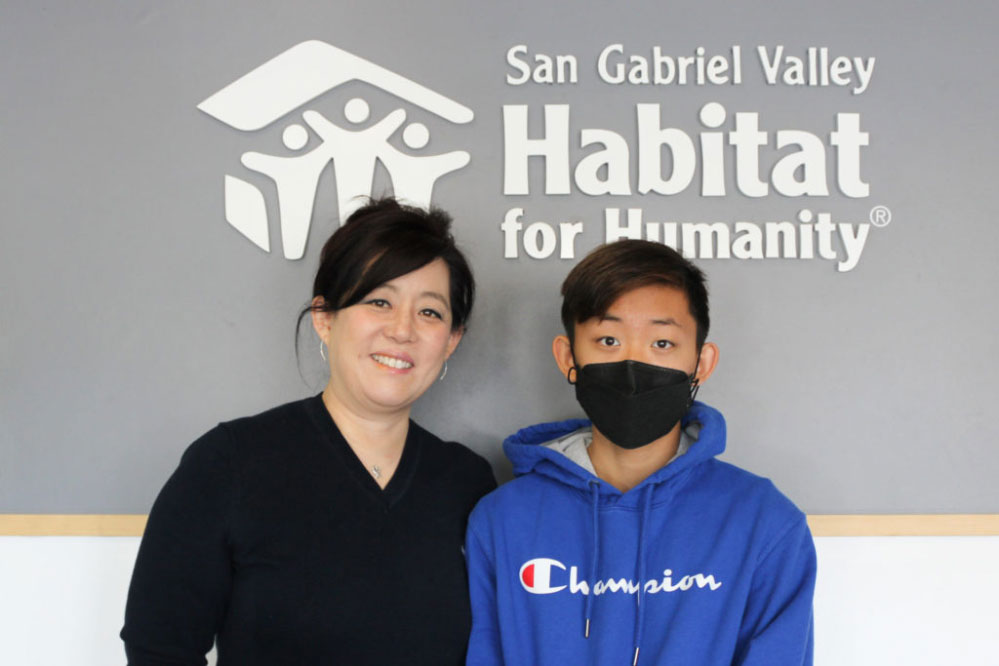 Mom and her young son posing in front of the San Gabriel Valley Habitat for Humanity sign.