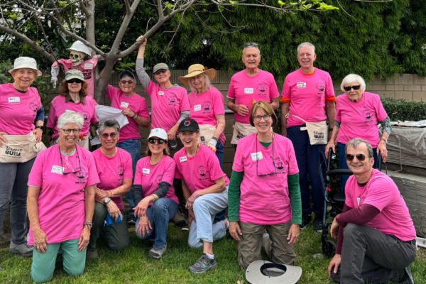 a group of women wearing pink shirts and hardhats posing for the camera