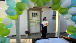 a woman stands in front of a front door surrounded by a balloon arch 