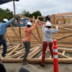 construction volunteers raising roof trusses