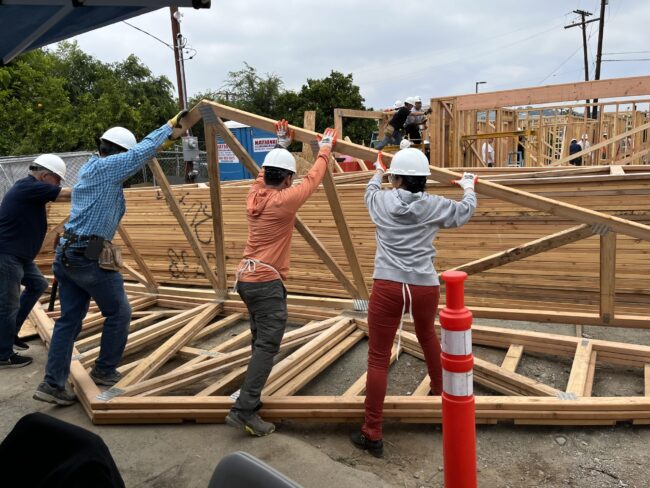 construction volunteers raising roof trusses