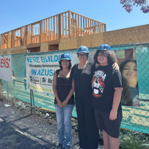 Michelle poses with two children in front of future family home