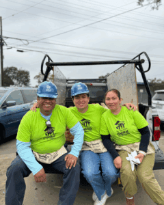 father, son and mother sitting on the back of a truck, hugging while posing for photo 