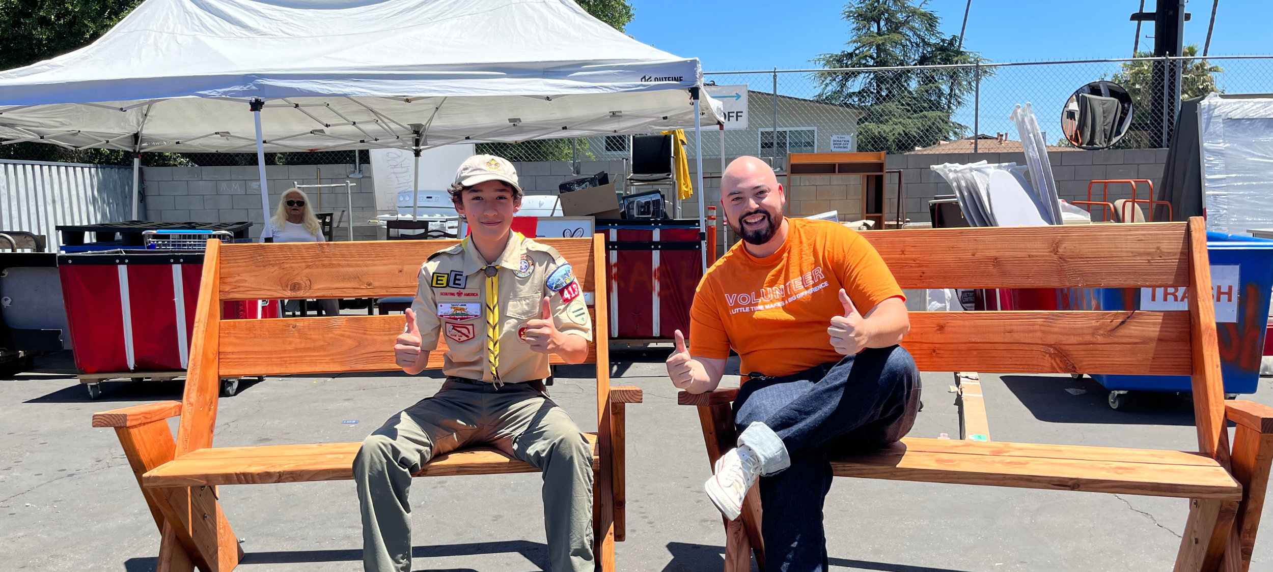 boy scout and man sitting on benches with thumbs up