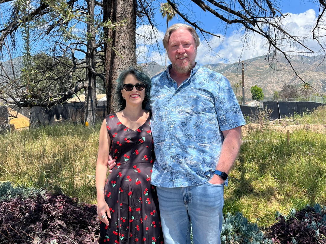 man and woman standing on a lot with grass and trees