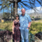 man and woman standing on a lot with grass and trees