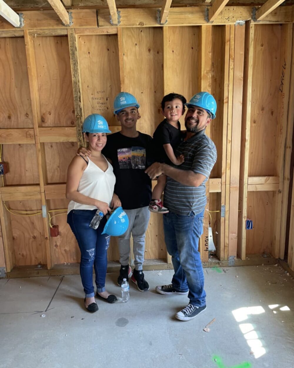 Family standing on the concrete floor of a home under construction