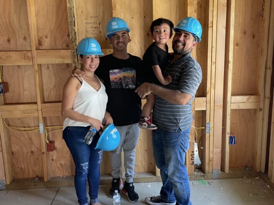 Family standing on the concrete floor of a home under construction