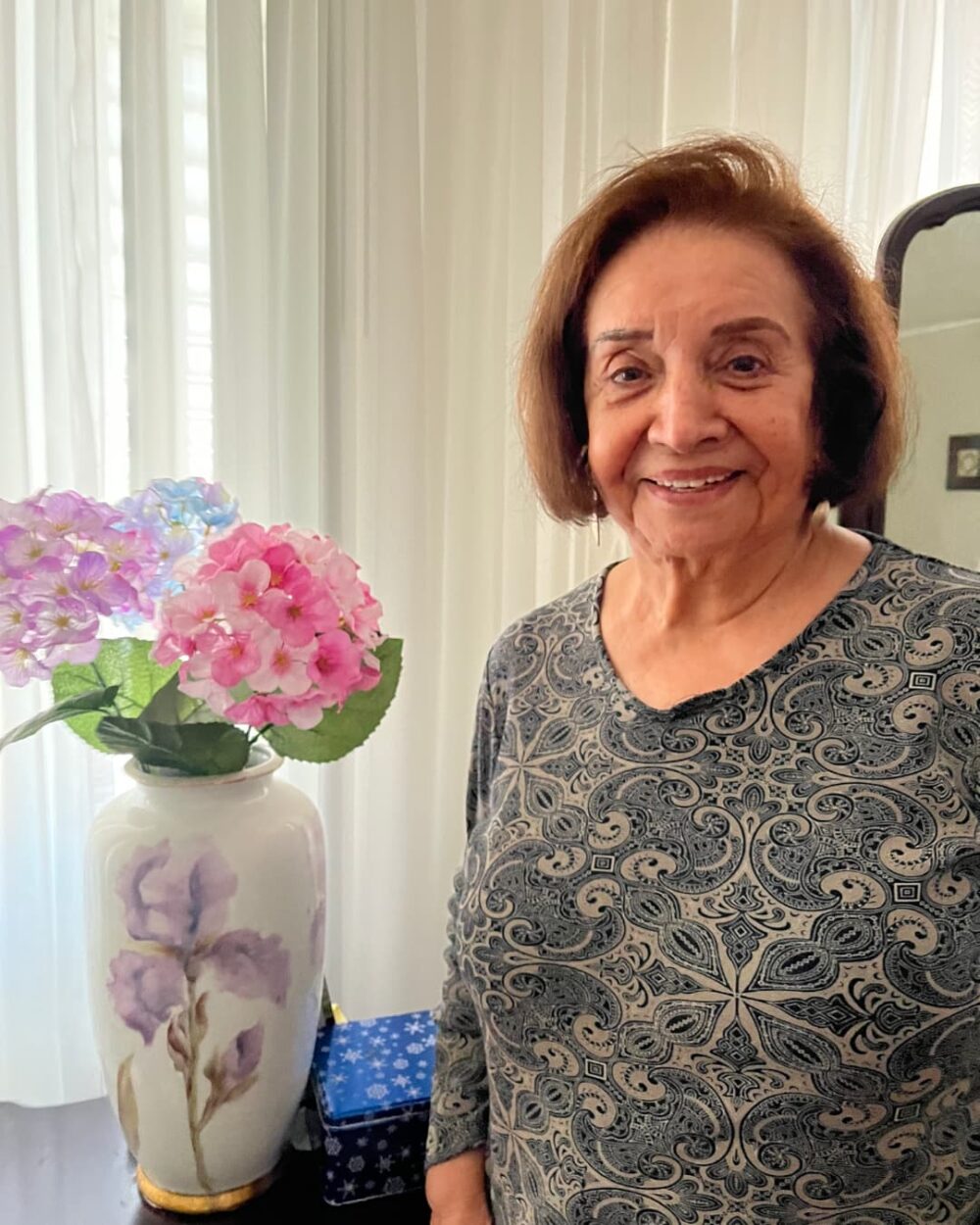 Woman smiling next to some pink and purple flowers