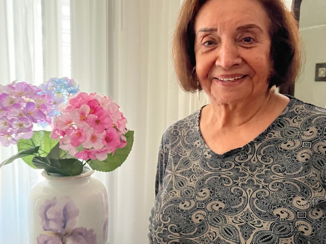 Woman smiling next to some pink and purple flowers