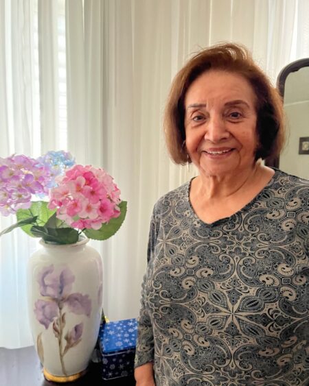 Woman smiling next to some pink and purple flowers