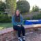 Jennifer A woman sitting on a brick fence and smiling