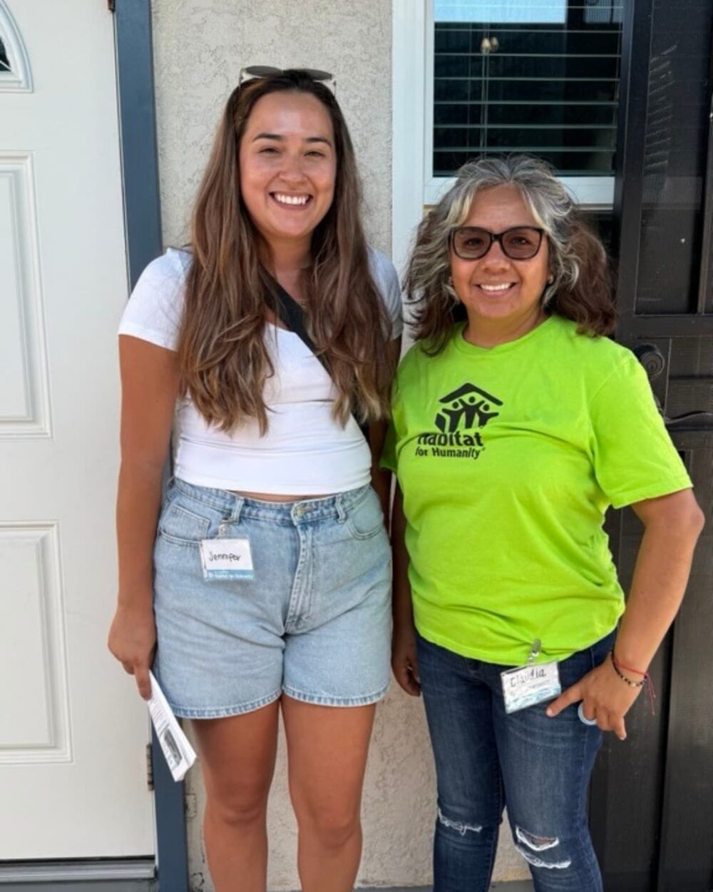 Two women smiling and standing in front of a home