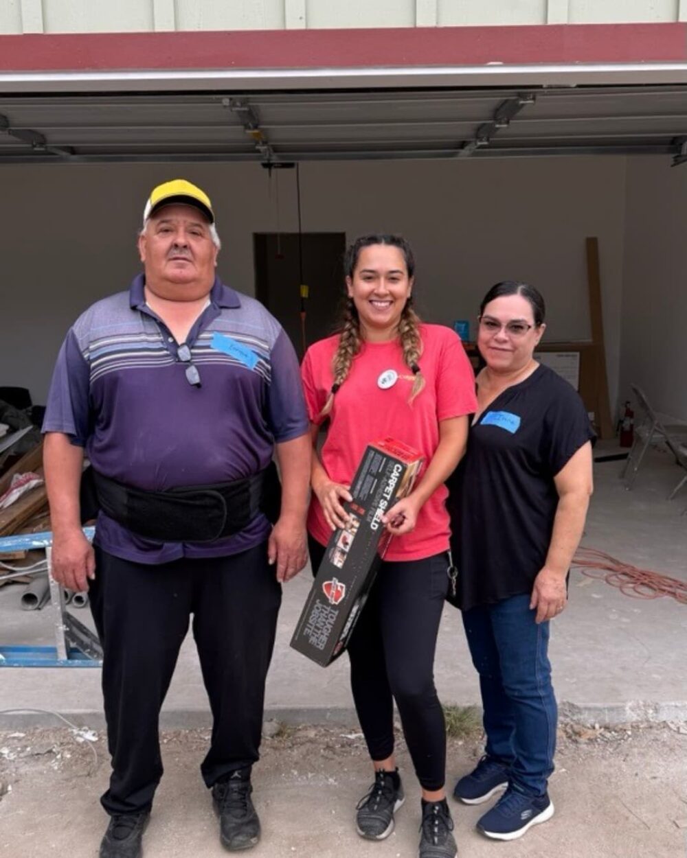 A woman holding a box and smiling between her parents