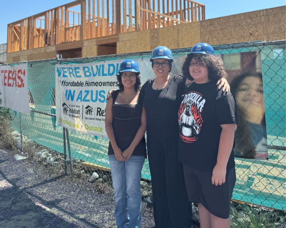 A group of three people standing in front of a building site that is under construction
