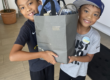 two young boys smiling holding a welcome home basket