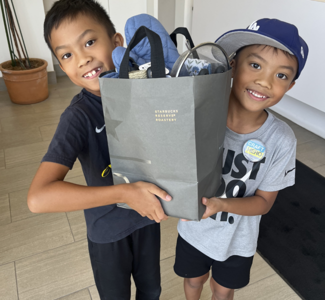 two young boys smiling holding a welcome home basket