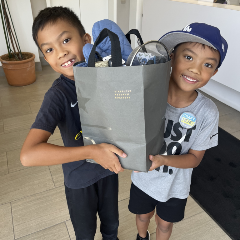 two young boys smiling holding a welcome home basket