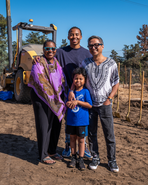 family standing, smiling at the groundbreaking