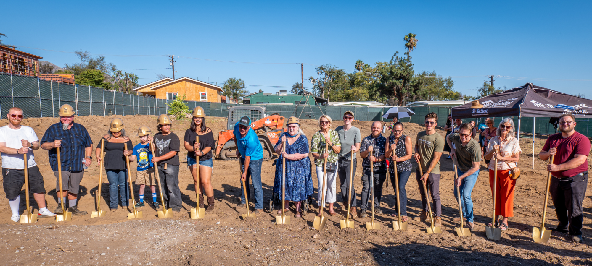 group of people standing on an empty lot holding shovels, depicting a groundbreaking ceremony