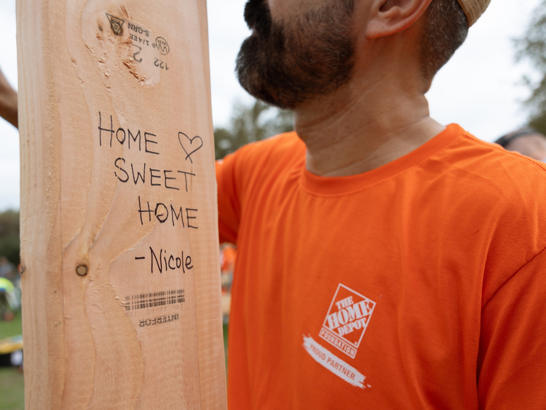 volunteer signing a wall - with the message Home Sweet Home