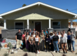 group of 25 people standing in front of a newly rebuilt home