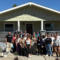 group of 25 people standing in front of a newly rebuilt home