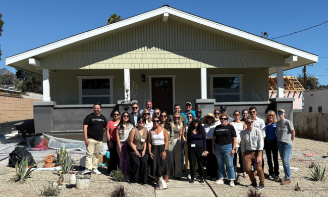 Rebuilding with Resilience group of 25 people standing in front of a newly rebuilt home