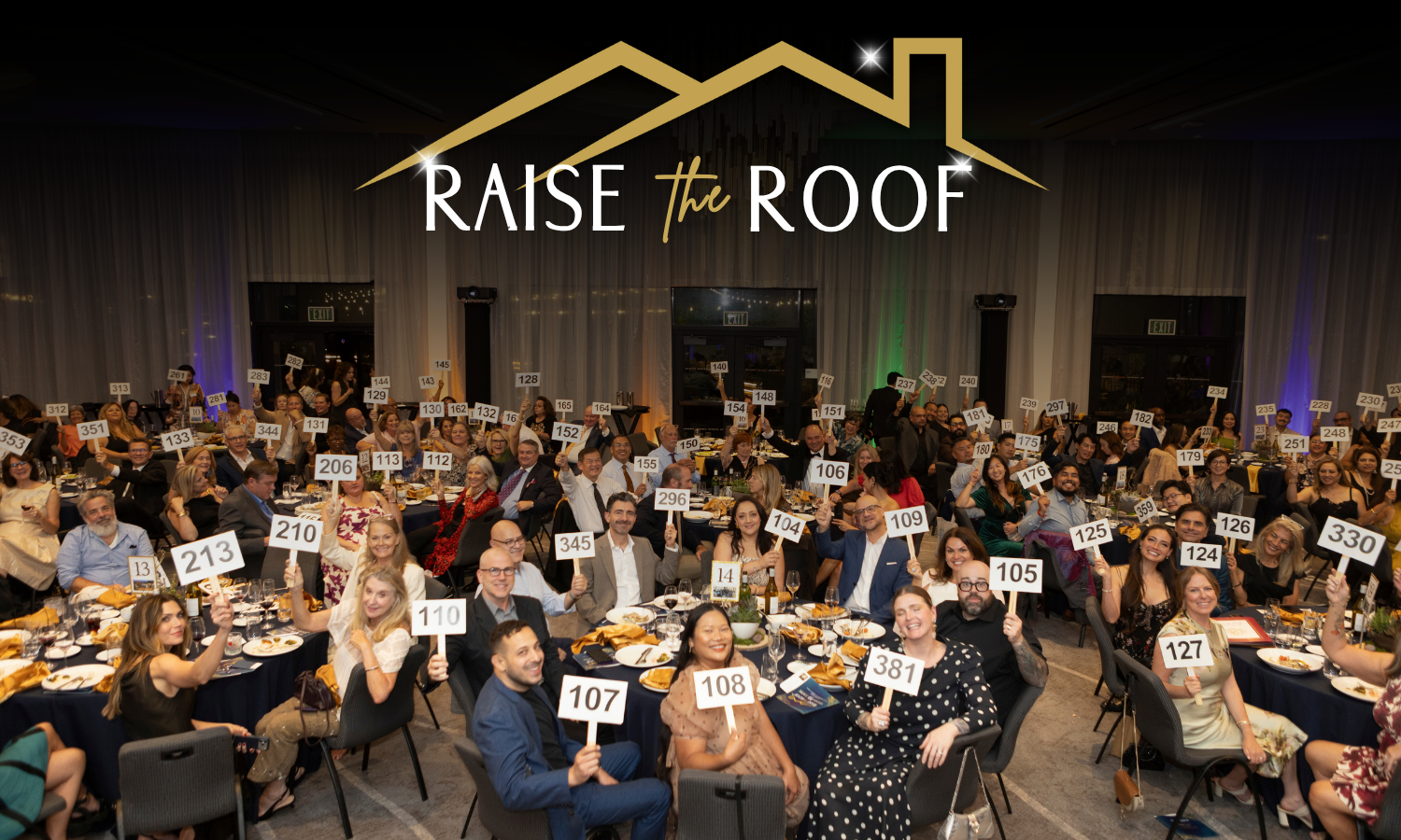crowd of people holding auction paddles at the gala